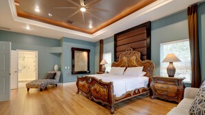 A spacious bedroom with a large bed, a chair, a dresser, and a nightstand. - Contemporary Brandon Home w/ Pool & Game Room (Brandon)