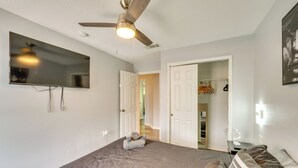 A bedroom with a bed, a ceiling fan, a TV mounted on the wall, and a closet with hanging clothes. - Chic Florida Retreat ~ 7 Mi to Walt Disney World! (Kissimmee)