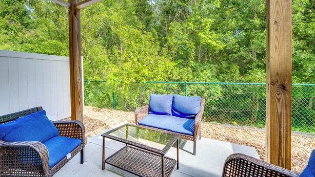 An outdoor patio with wicker furniture and a glass table, surrounded by a wooden pergola and a green fence. - Chic Florida Retreat ~ 7 Mi to Walt Disney World! (Kissimmee)