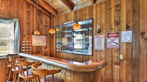 A wooden bar area with a long counter, multiple stools, and hanging pendant lights. - Sandford Vacation Rental Near Airport & Lake! (Sanford)