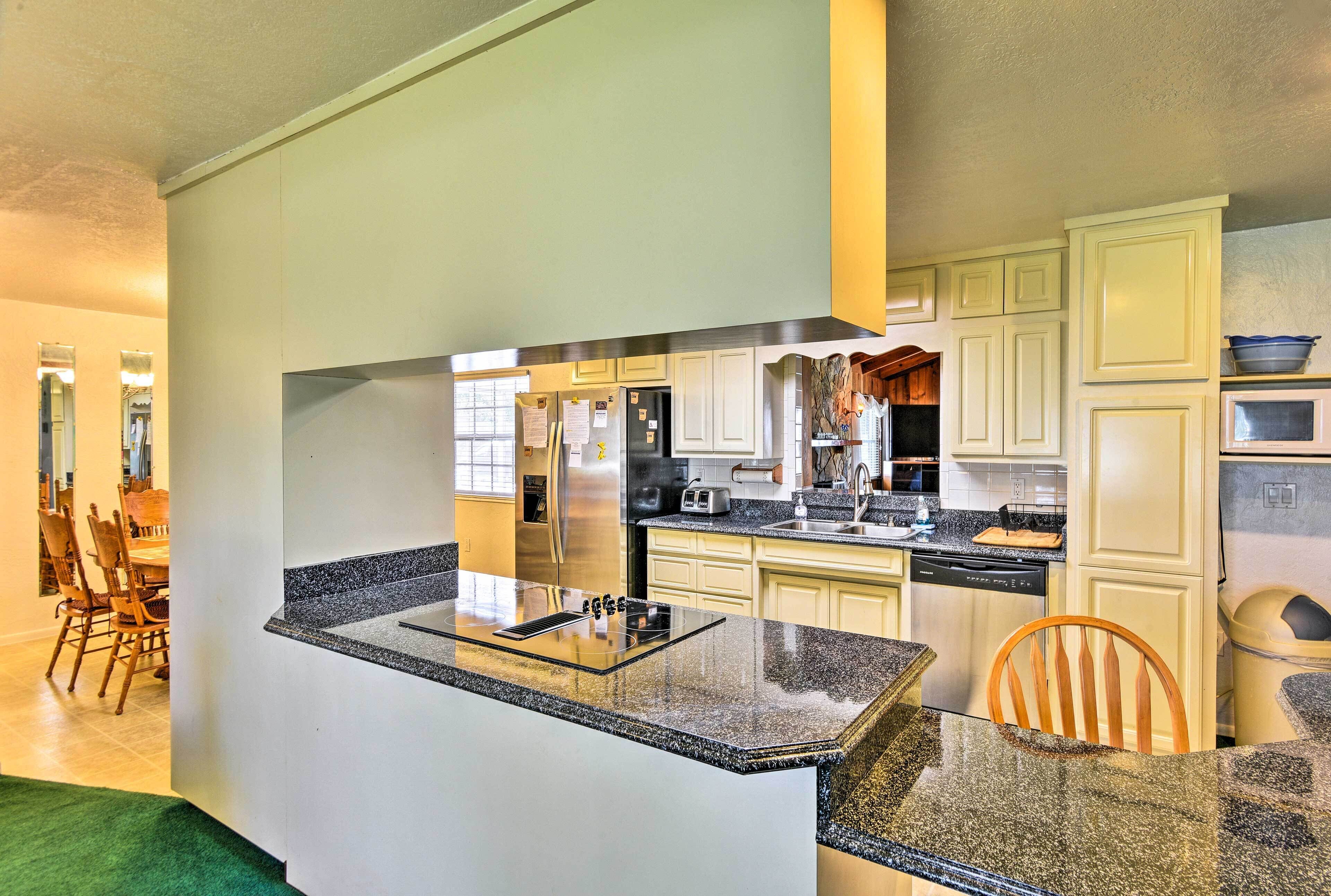 Una cocina moderna con encimeras de granito, muebles blancos y electrodomésticos de acero inoxidable.