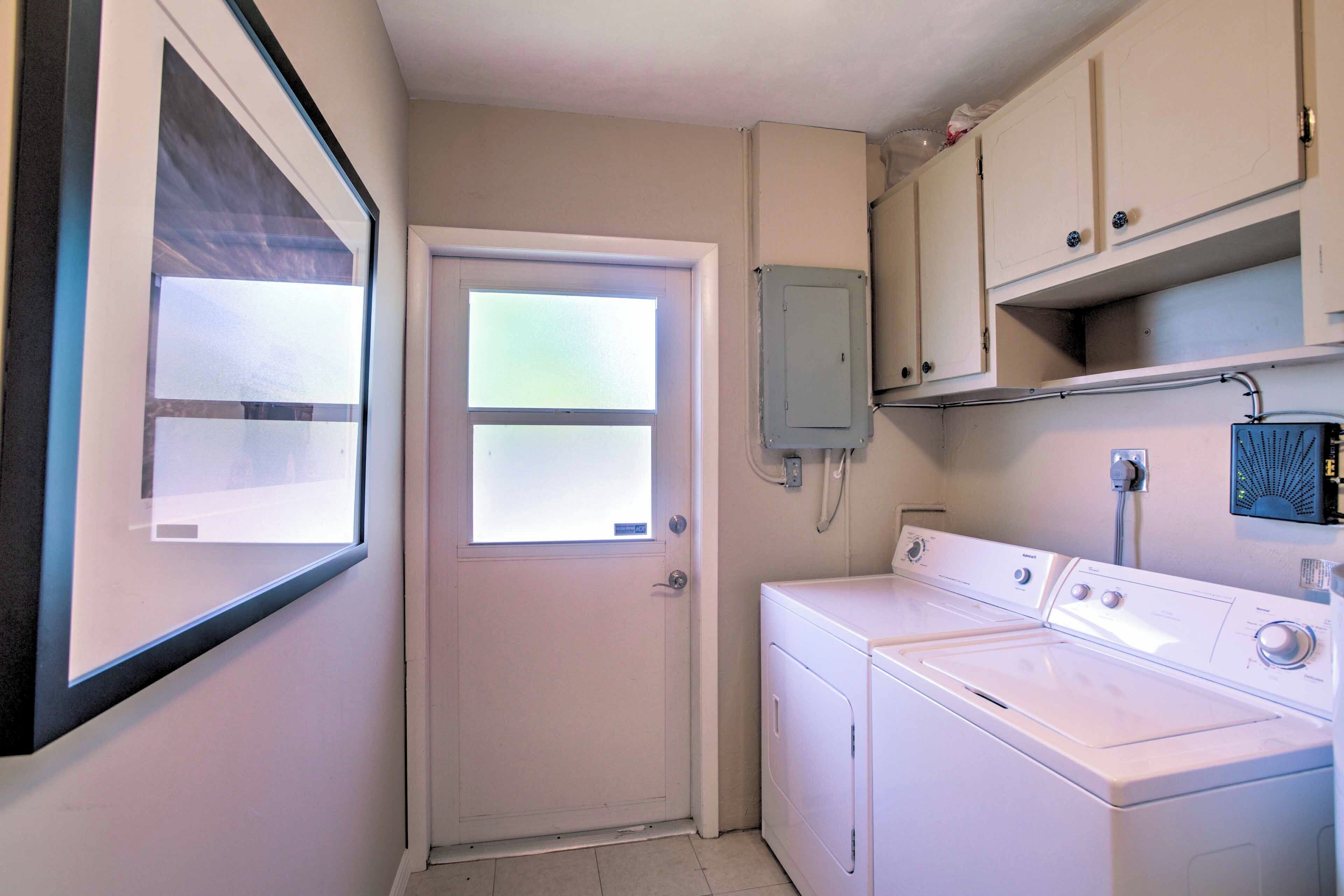 A laundry room with a washing machine, a dryer, and a small cabinet.