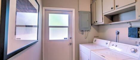 A laundry room with a washing machine, a dryer, and a small cabinet.