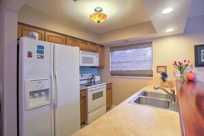 A kitchen with a refrigerator, microwave, stove, and sink.