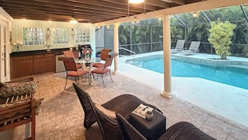 An outdoor patio with a pool, dining area, and kitchen.