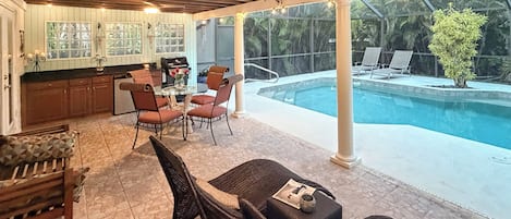 Un patio al aire libre con piscina, zona de comedor y cocina.
