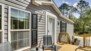 A wooden deck with outdoor furniture, a door, and windows.