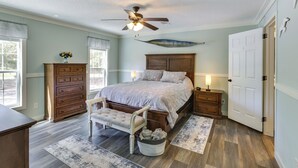 A bedroom with a bed, a ceiling fan, a dresser, a chair, and a nightstand.