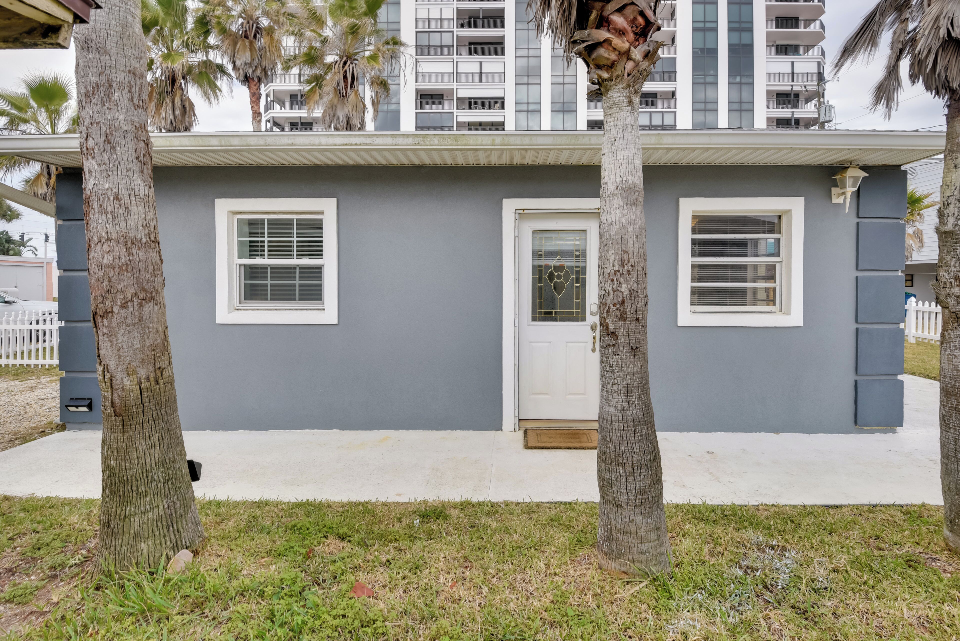 A modern two-story house with a gray facade, white door, and windows with white frames.