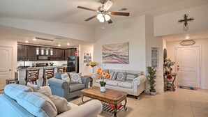 A spacious living room with a sofa set, a coffee table, and a dining area with chairs and a kitchen in the background. - Charming Poinciana House w/ Patio: 30 Mi to Disney (Kissimmee)