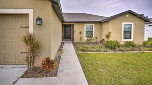 A residential house with a garage, a front door, and a small garden with plants and a lawn. - Charming Poinciana House w/ Patio: 30 Mi to Disney (Kissimmee)
