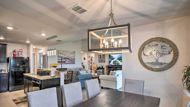 A modern kitchen with a built-in refrigerator, a dining area with a dark wooden table and matching chairs, and a living room with a sofa and a TV. - Charming Poinciana House w/ Patio: 30 Mi to Disney (Kissimmee)