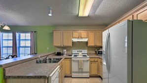 A kitchen with wooden cabinets, a white stove, a Samsung refrigerator, and a granite countertop. - Cute Pensacola Townhome ~ 9 Mi to Downtown! (Pensacola)