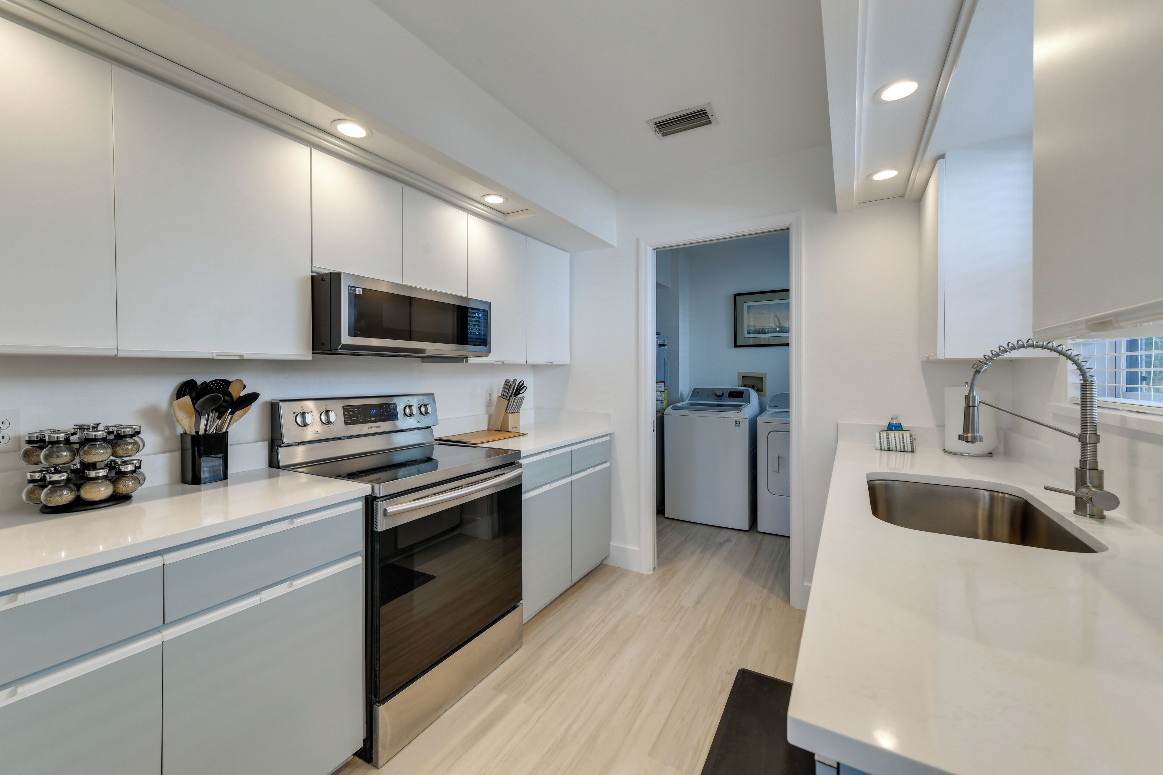 A modern kitchen with stainless steel appliances, white cabinetry, and a built-in microwave.