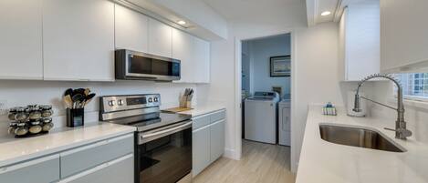 A modern kitchen with stainless steel appliances, white cabinetry, and a built-in microwave.