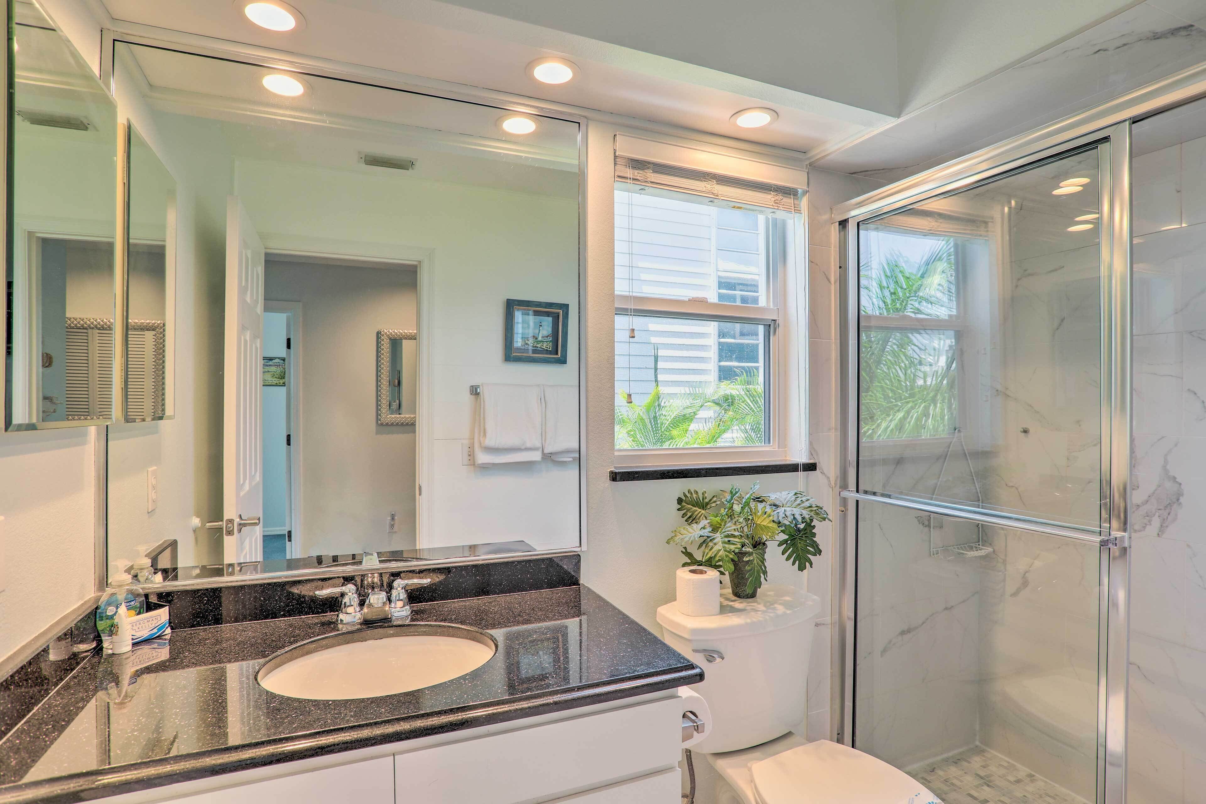 A modern bathroom with a large mirror, a sink, a toilet, and a shower.