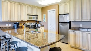 A kitchen with granite countertops, stainless steel appliances, and light-colored cabinetry. - Cozy Miramar Beach Condo w/ Pools & Beach Access! (Miramar Beach)