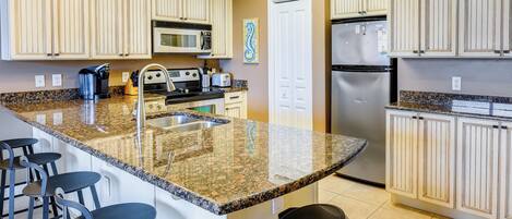 A kitchen with granite countertops, stainless steel appliances, and light-colored cabinetry.