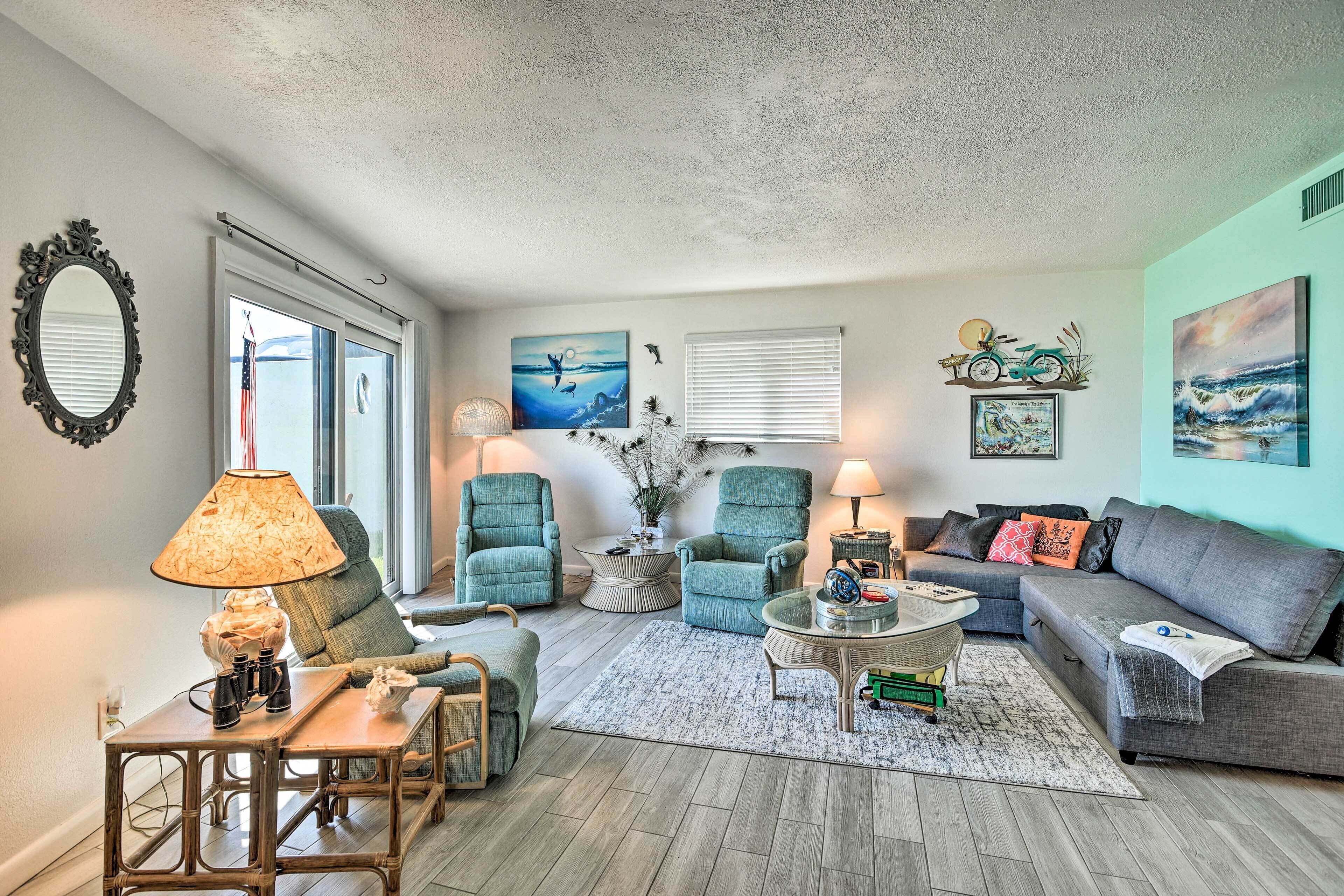 A living room with a large window, two armchairs, a sofa, a coffee table, and a lamp.