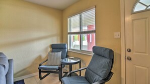 A corner room with two grey armchairs, a small round table, and a window with blinds. - Cozy Indian Rocks Beach Condo - Steps to Beach! (Indian Rocks Beach)