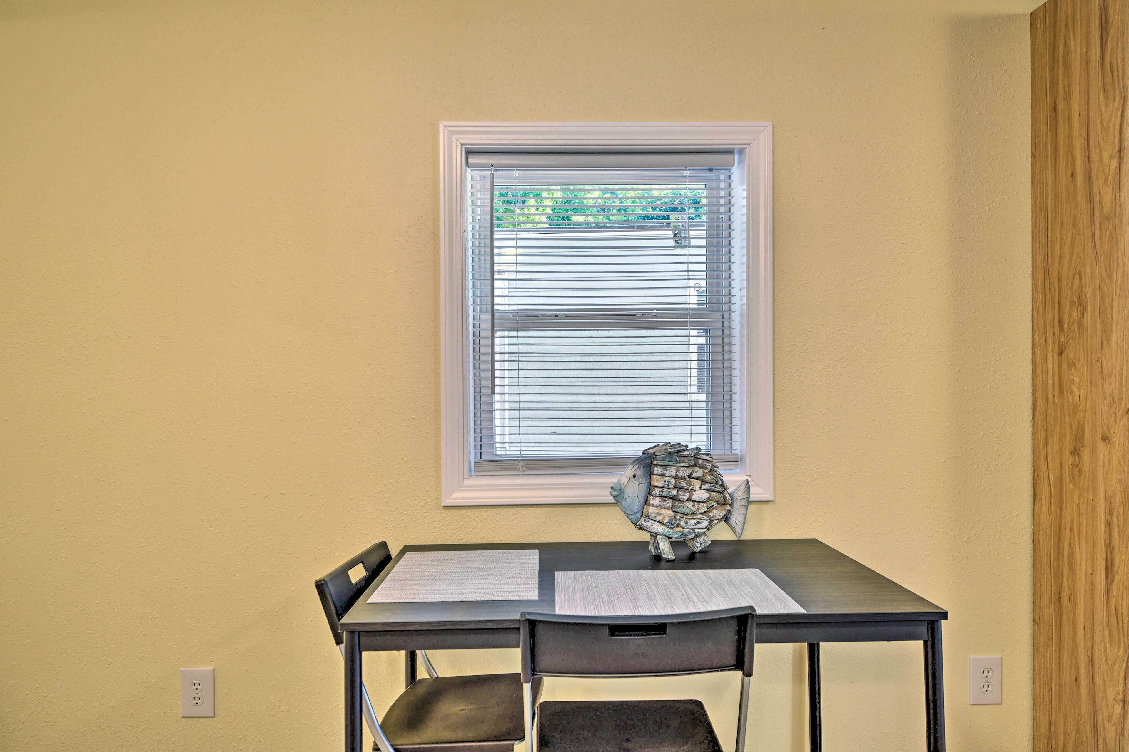 A small dining table with two chairs, a fish decoration, and papers on the table.