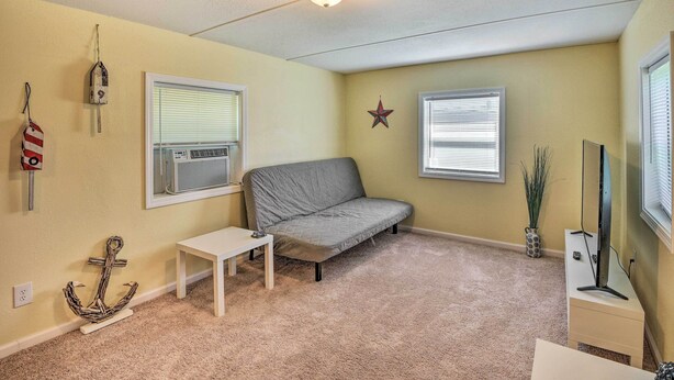 A cozy living room with a gray sofa, a small white table, and a ceiling light fixture. - Daytona Beach Home ~ 4 Mi to Daytona Speedway (Daytona Beach)