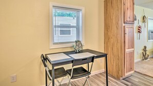 A room with a desk, two chairs, a window with blinds, and a wooden cabinet. - Daytona Beach Home ~ 4 Mi to Daytona Speedway (Daytona Beach)