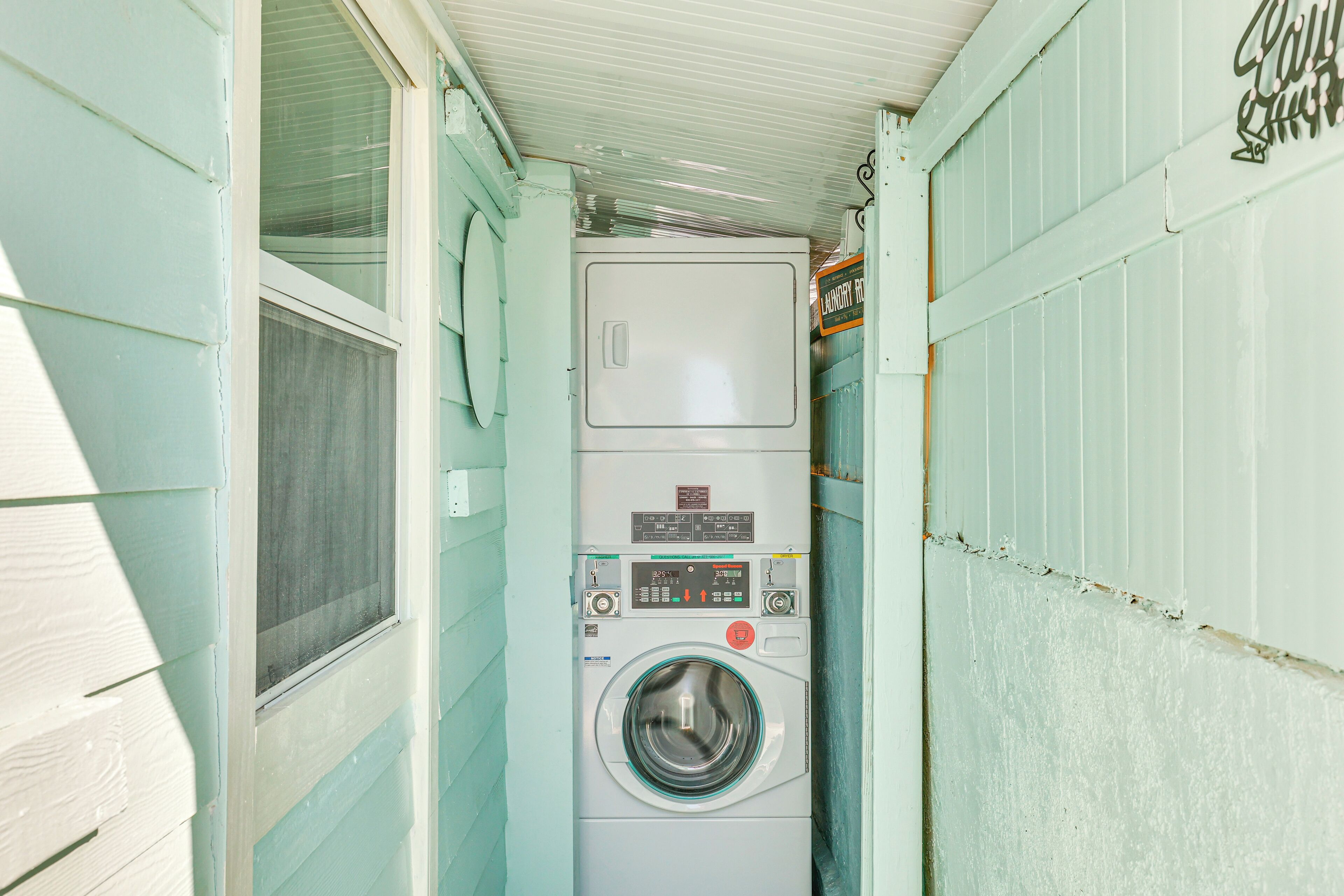 Une petite buanderie où la machine à laver et le sèche-linge sont placés l’un au-dessus de l’autre.