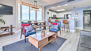A modern living room with a large window, a dining area, and a kitchen with a bar. - Family Resort Condo w/ 2 Pools: 1 Mi to Disney! (Orlando)