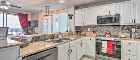 A modern kitchen with white cabinets, a stainless steel oven, and a microwave.