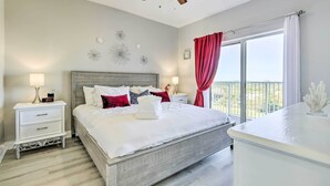 A bedroom with a bed, nightstands, a ceiling fan, a window with curtains, and decorative wall art. - Family Resort Condo w/ 2 Pools: 1 Mi to Disney! (Orlando)