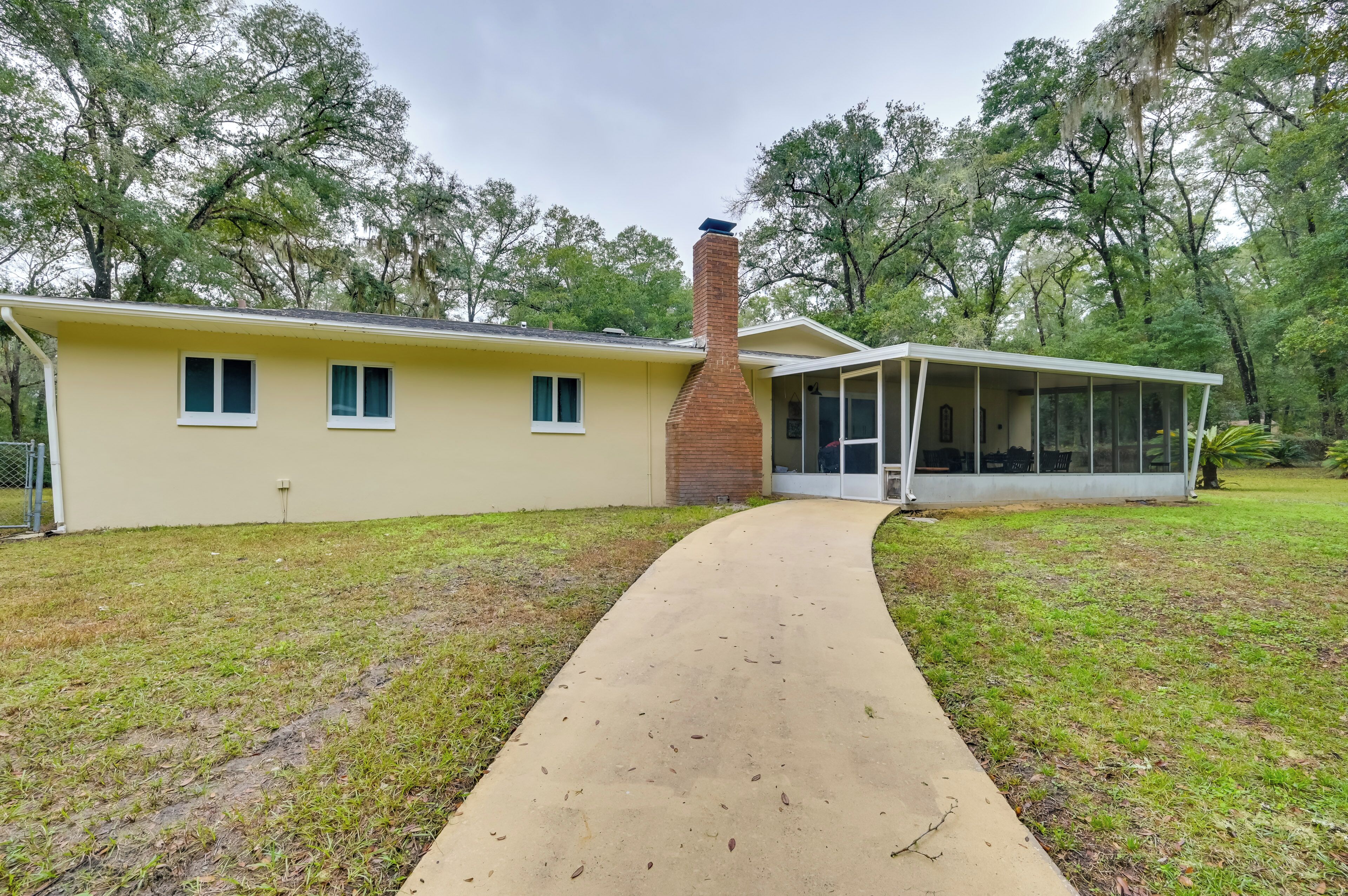 A single-story house with a brick chimney, a covered porch, and a paved driveway.