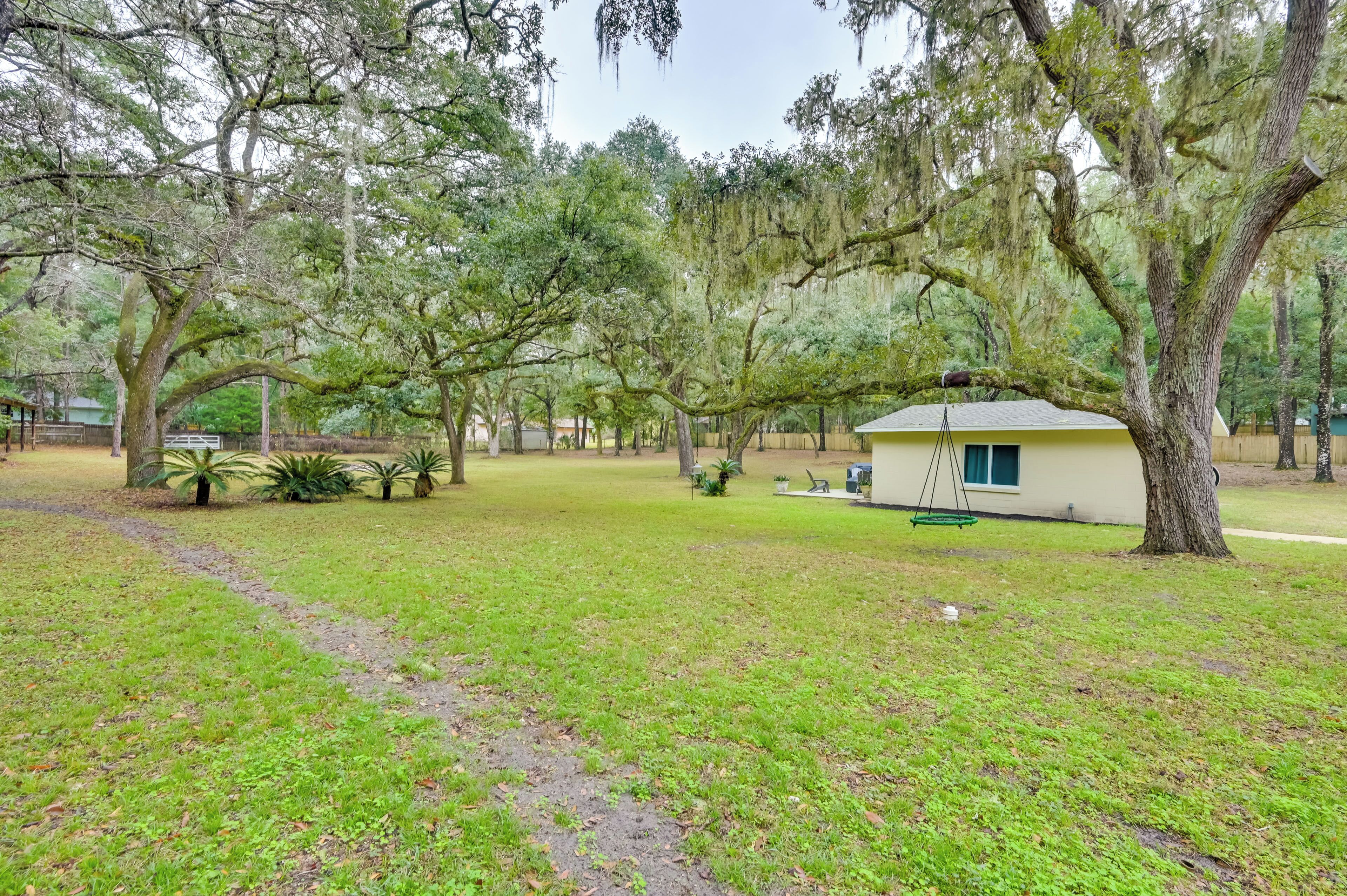 A small, single-story building with a porch, surrounded by mature trees and a grassy area.