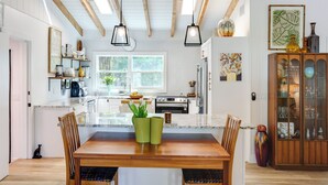 A modern kitchen with wooden beams, a central island, and pendant lighting.