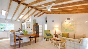 A spacious living area with a wooden ceiling, a dining table with chairs, a sofa, and a coffee table.