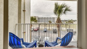 A balcony with blue chairs, a view of a parking lot, and a building in the background. - Daytona Beach Studio w/ Private Lanai 1 Mi to Pier (Daytona Beach)