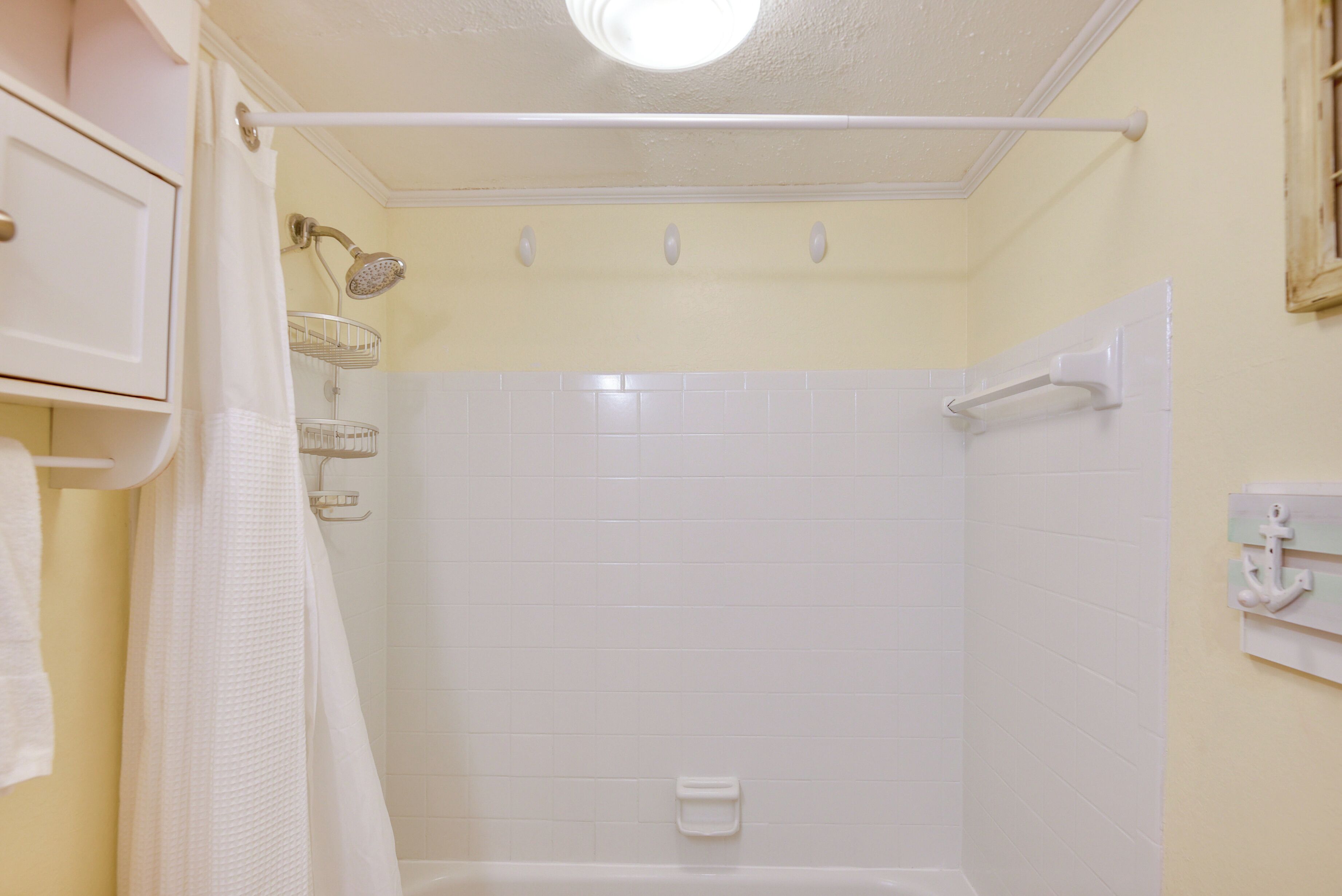 A bathroom with a shower, a towel rack, and a white bathtub.
