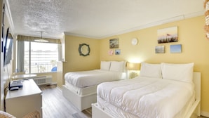 A hotel room with two beds, a desk, and a window with curtains. - Daytona Beach Studio w/ Private Lanai 1 Mi to Pier (Daytona Beach)