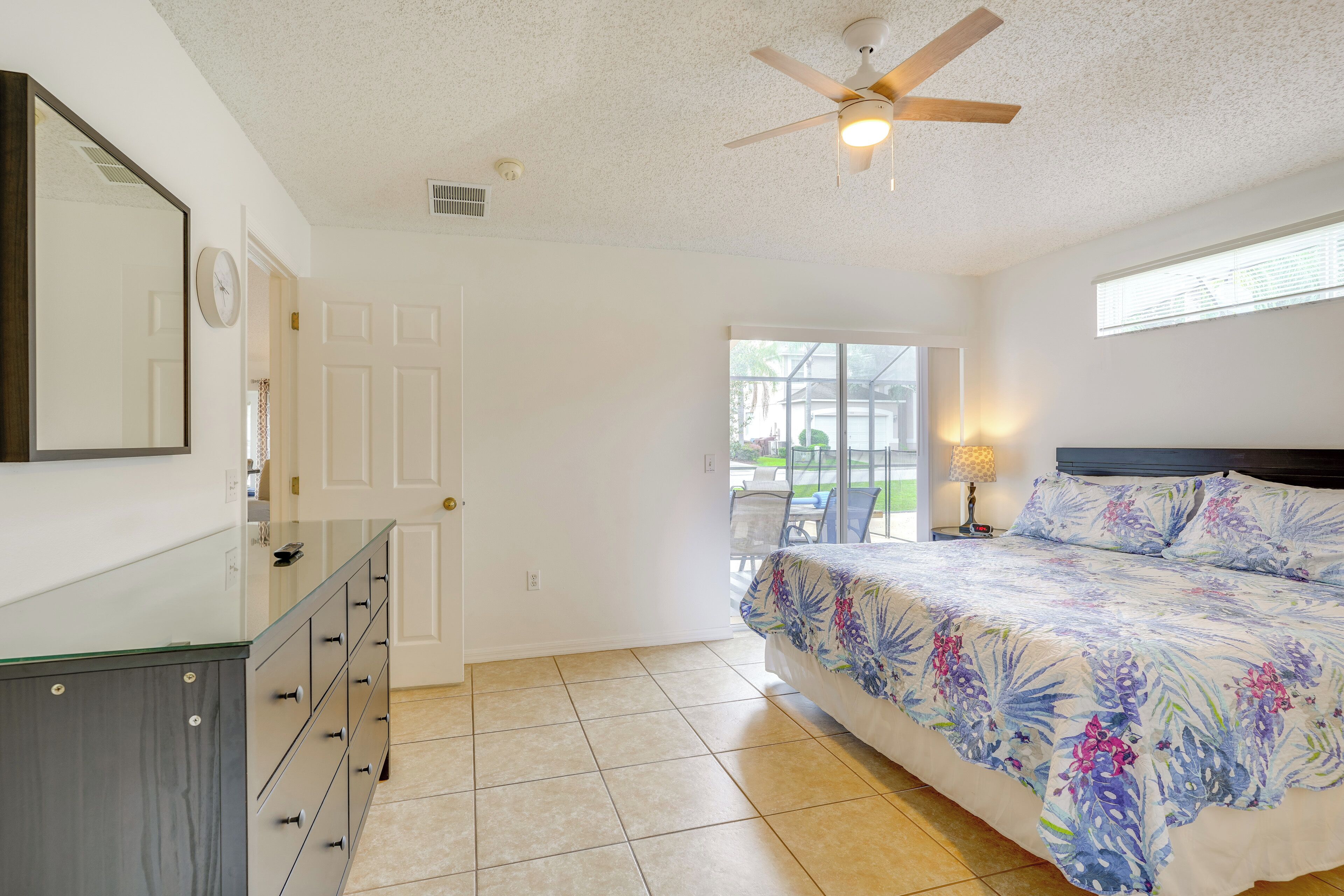 A bedroom with a bed, a ceiling fan, a dresser, and a window with blinds.