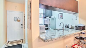 A modern kitchen with granite countertops, stainless steel appliances, and a built-in oven. - Idyllic Apt w/ Pool Access - Walk to Beach! (Lauderdale-by-the-Sea)