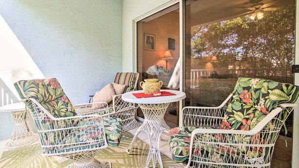 A patio with white wicker chairs and a table, a sliding glass door leading to a balcony, and a lamp on the table. - Idyllic Apt w/ Pool Access - Walk to Beach! (Lauderdale-by-the-Sea)