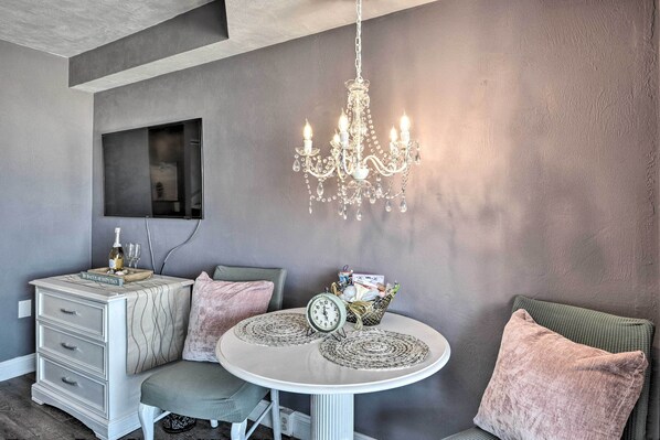 A room with a chandelier, a table with a clock, a dresser, and a chair. - Community Perks! Dreamy Daytona Studio (Daytona Beach)