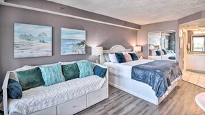 A bedroom with two beds, a sofa, and artwork on the wall.