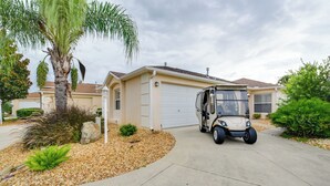 A residential driveway with a golf cart parked in front of a house with a garage. - The Villages Home on Golf Course Near Lake Sumter! (The Villages)