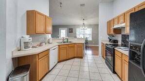 A kitchen with wooden cabinets, a dishwasher, a refrigerator, and a stove. - Deltona Retreat w/ Yard + Grill: Pets Welcome! (Deltona)