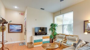 Ein Wohnzimmer mit einer Couch, Sesseln, einem Fernseher, einer Pflanze und einem Kamin.
