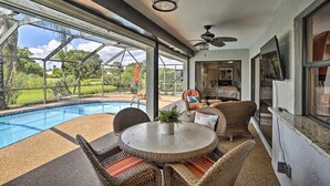 A covered outdoor area with a pool, wicker furniture, and a ceiling fan. - Pet-friendly Fort Myers Home w/ Patio & Grill! (North Fort Myers)