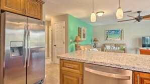 A kitchen with a stainless steel refrigerator, wooden cabinets, a granite countertop, and pendant lighting. - Pet-friendly Fort Myers Home w/ Patio & Grill! (North Fort Myers)