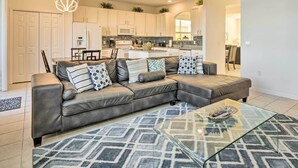 Moderni olohuone, jossa on nahkainen kulmasohva, lasinen sohvapöytä ja kuviollinen matto.