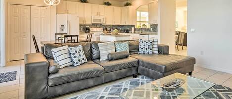 A modern living room with a leather sectional sofa, a glass coffee table, and a patterned rug.